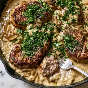 Close-up of golden-brown seared pork medallions in a velvety light-tan onion sauce. (pork medallions in onion gravy)