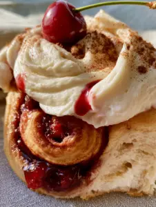 Extreme macro close-up of Cherry Cinnamon Rolls showing pull-apart dough, air pockets, and glossy cherry filling. (Cherry Cinnamon Rolls)