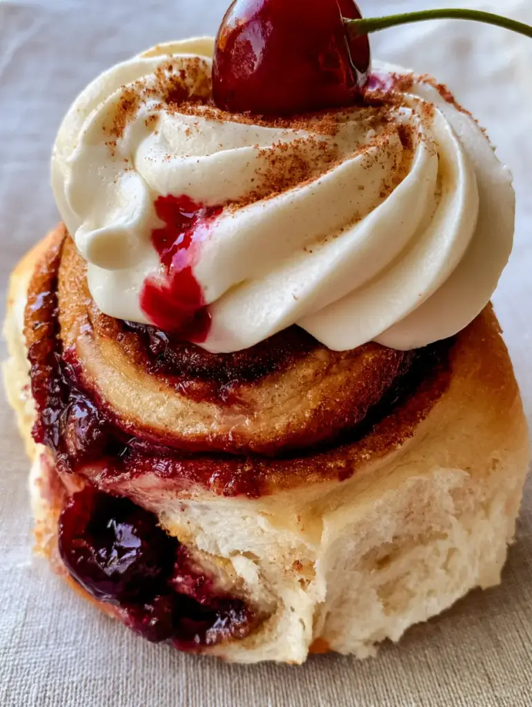 Cherry Cinnamon Rolls with Tart Filling and Velvet Cream Cheese Frosting 1 Detailed view of velvet cream cheese frosting swooshes on Cherry Cinnamon Rolls with red cherry juice bleed.