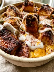 Close-up of toasted grain-free bread cubes with golden charred edges and orange zest flecks in a Paleo Pumpkin Bread Pudding.